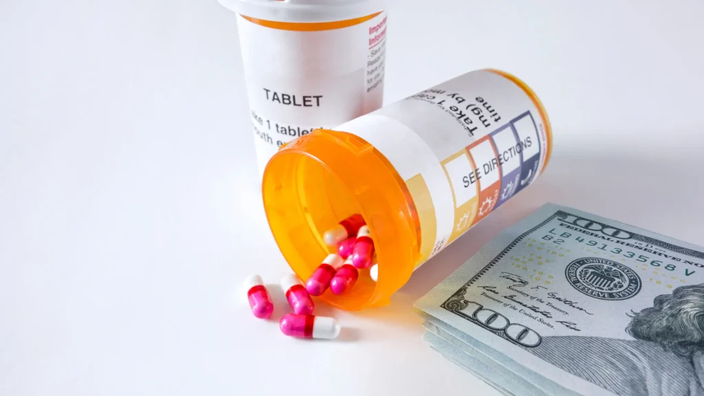 Pill medication sitting sideways out of pill bottle next to stack of bills