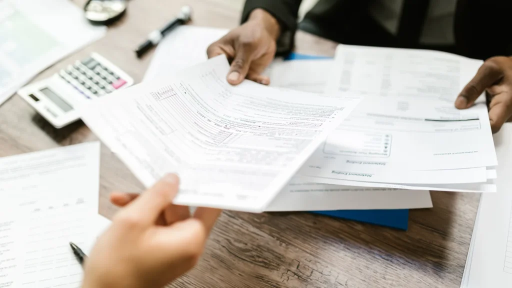 two people passing tax documents to meet the 2025 tax deadlines